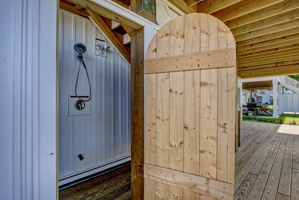 A wooden door is open to a outdoor shower.