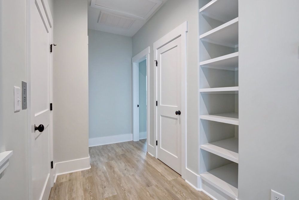 A hallway with a lot of shelves and doors in a house.