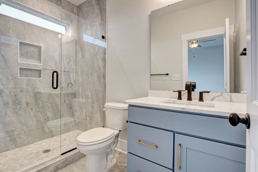 A bathroom with a toilet , sink , mirror and walk in shower.