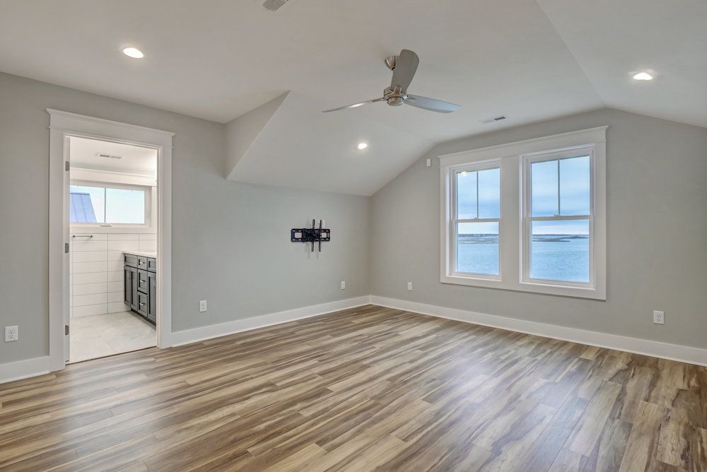 A large empty room with hardwood floors and a ceiling fan.