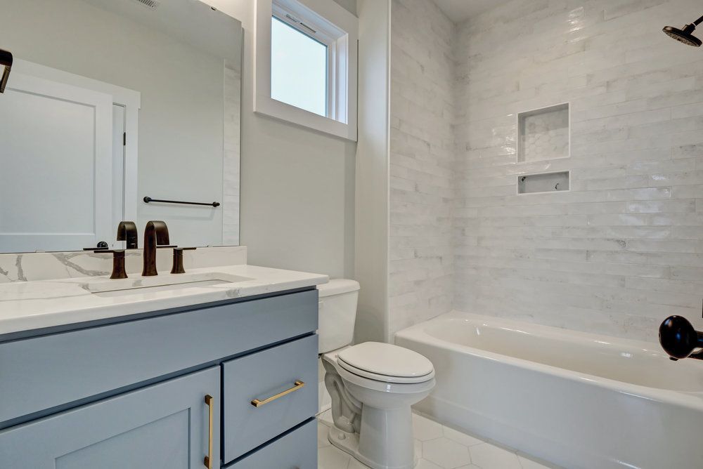 A bathroom with a toilet , sink , tub and mirror.