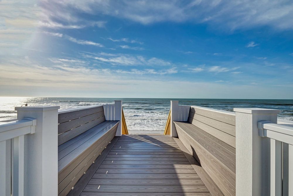 A wooden walkway leading to the ocean with benches.
