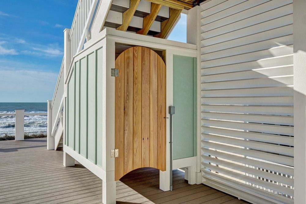 A wooden door is open to a beach shower.
