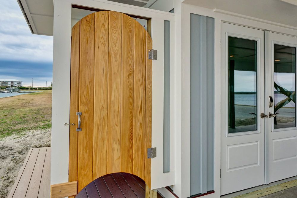 A wooden door is open on the side of a house.