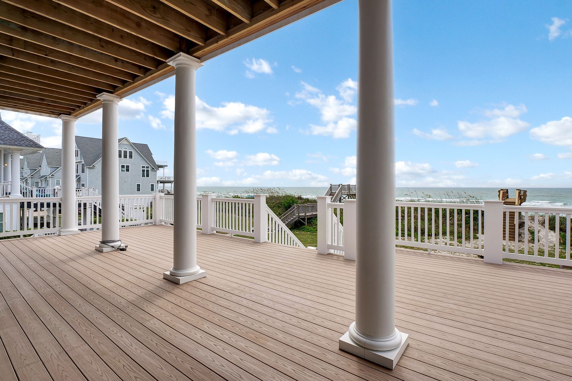 A large deck with columns and a view of the ocean