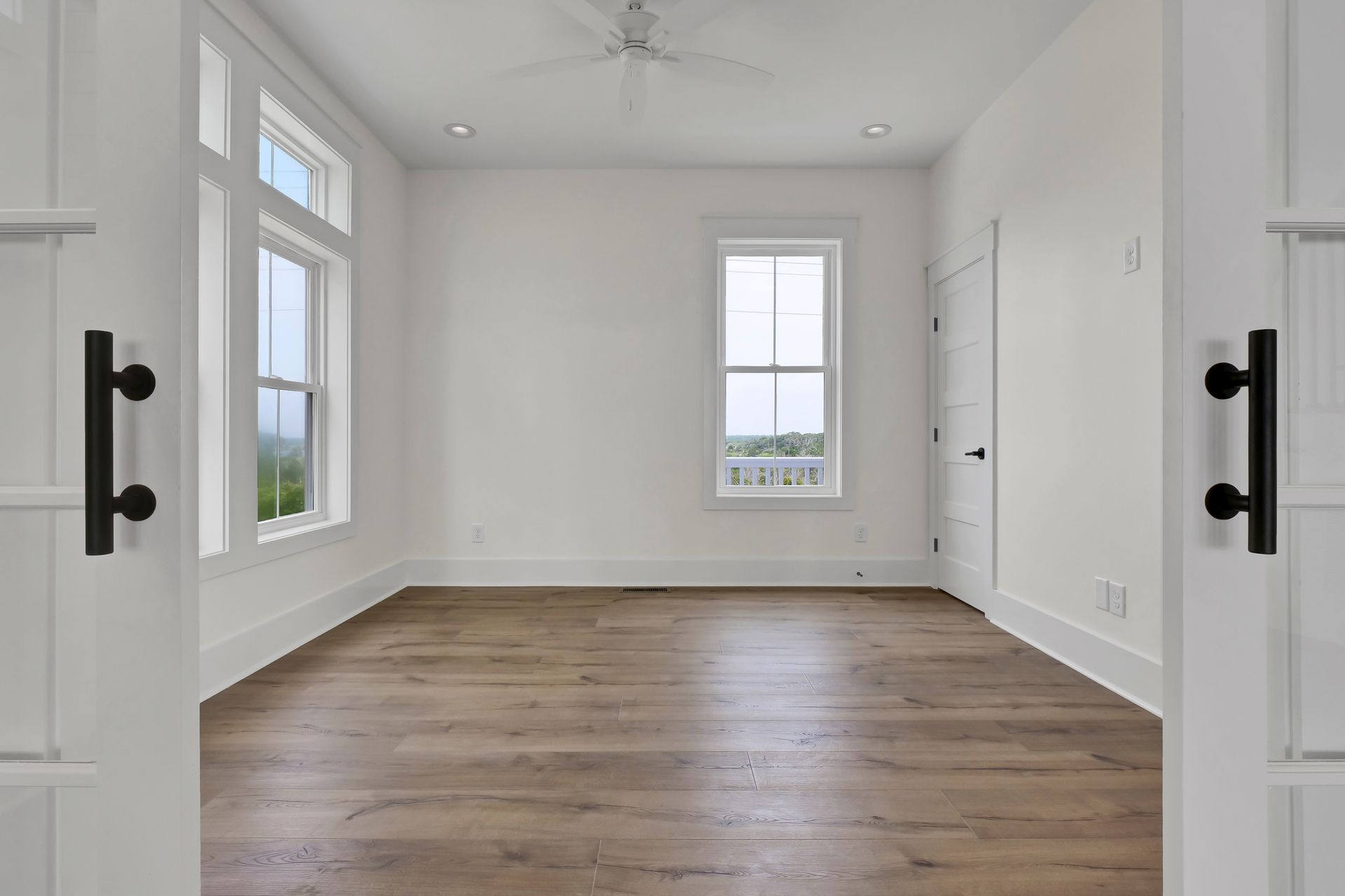 A large empty room with hardwood floors and white walls.