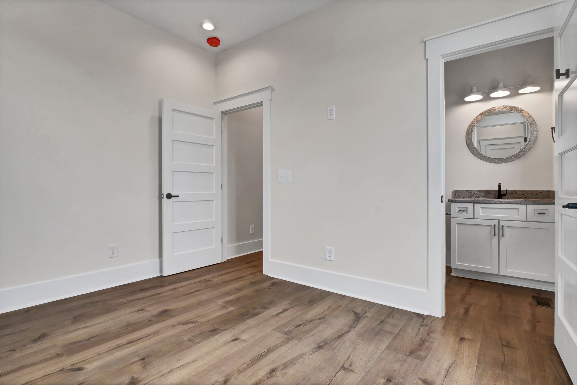 An empty room with hardwood floors and white cabinets in a house.
