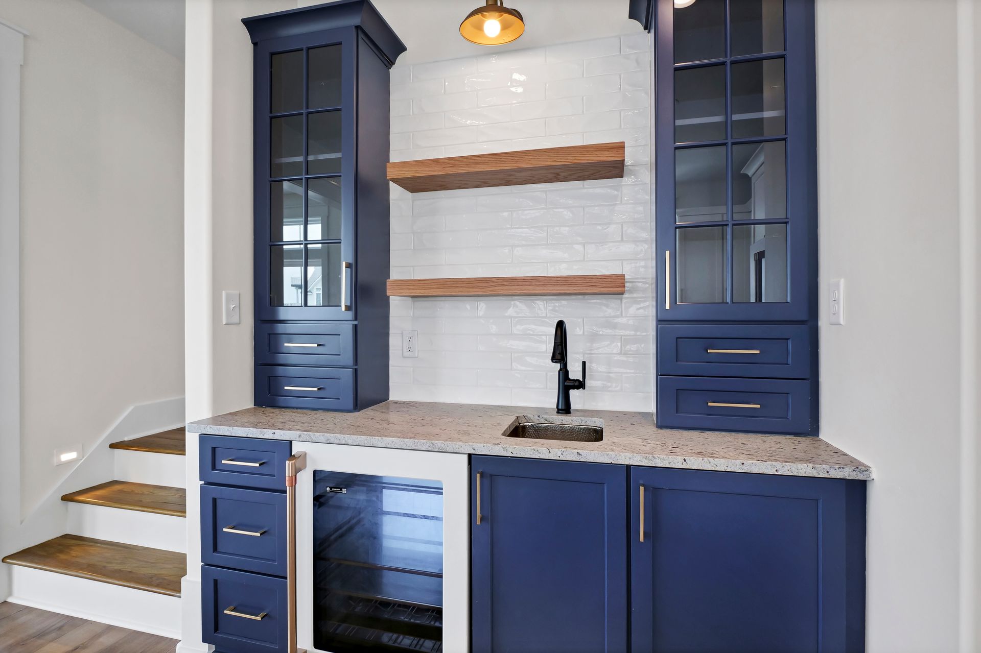 A kitchen with blue cabinets , a sink , and a refrigerator.