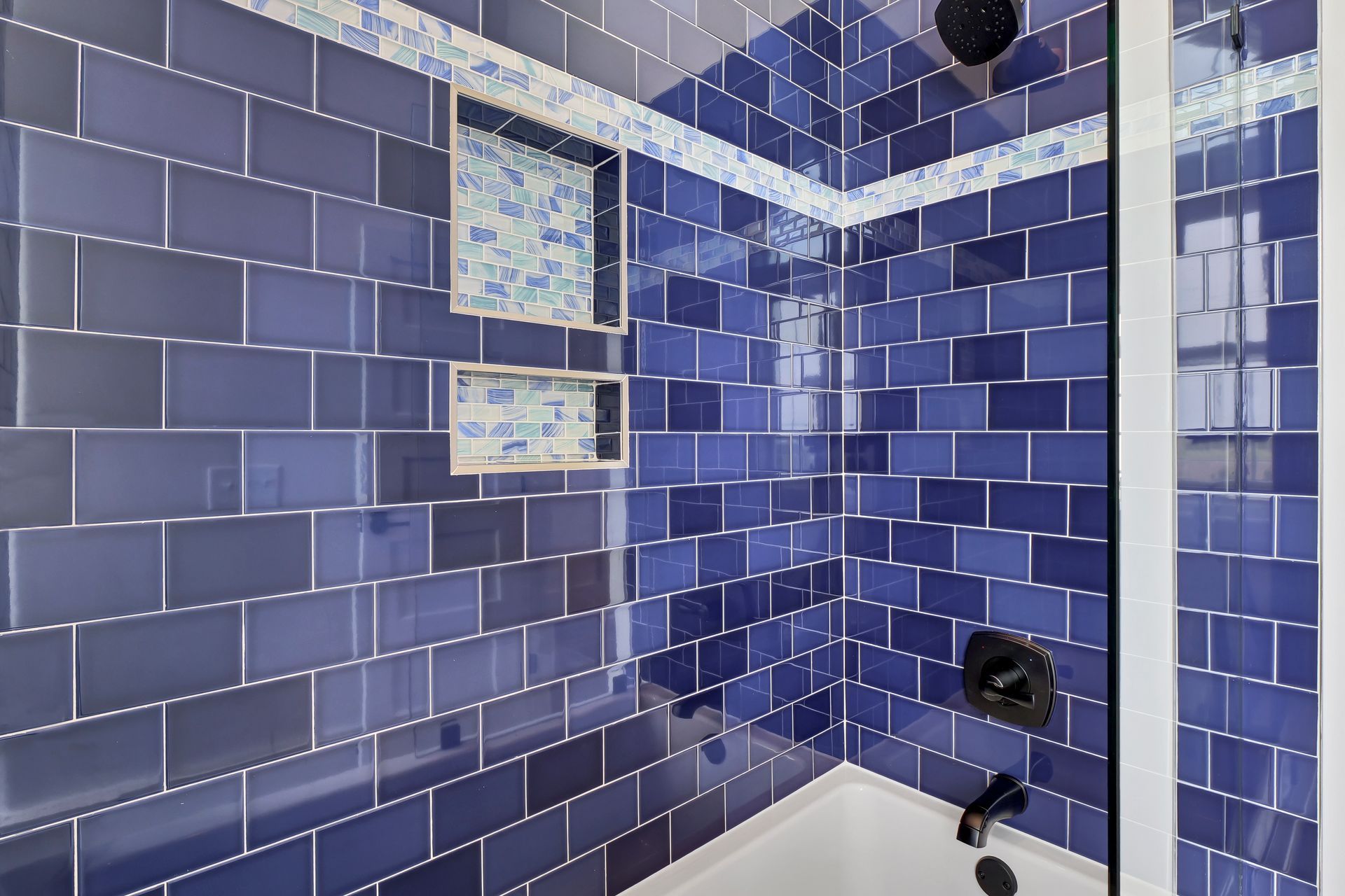 A bathroom with blue tiles and a bathtub