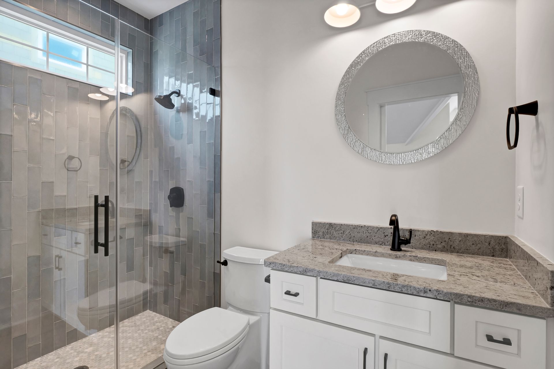 A bathroom with a toilet , sink , shower and mirror.