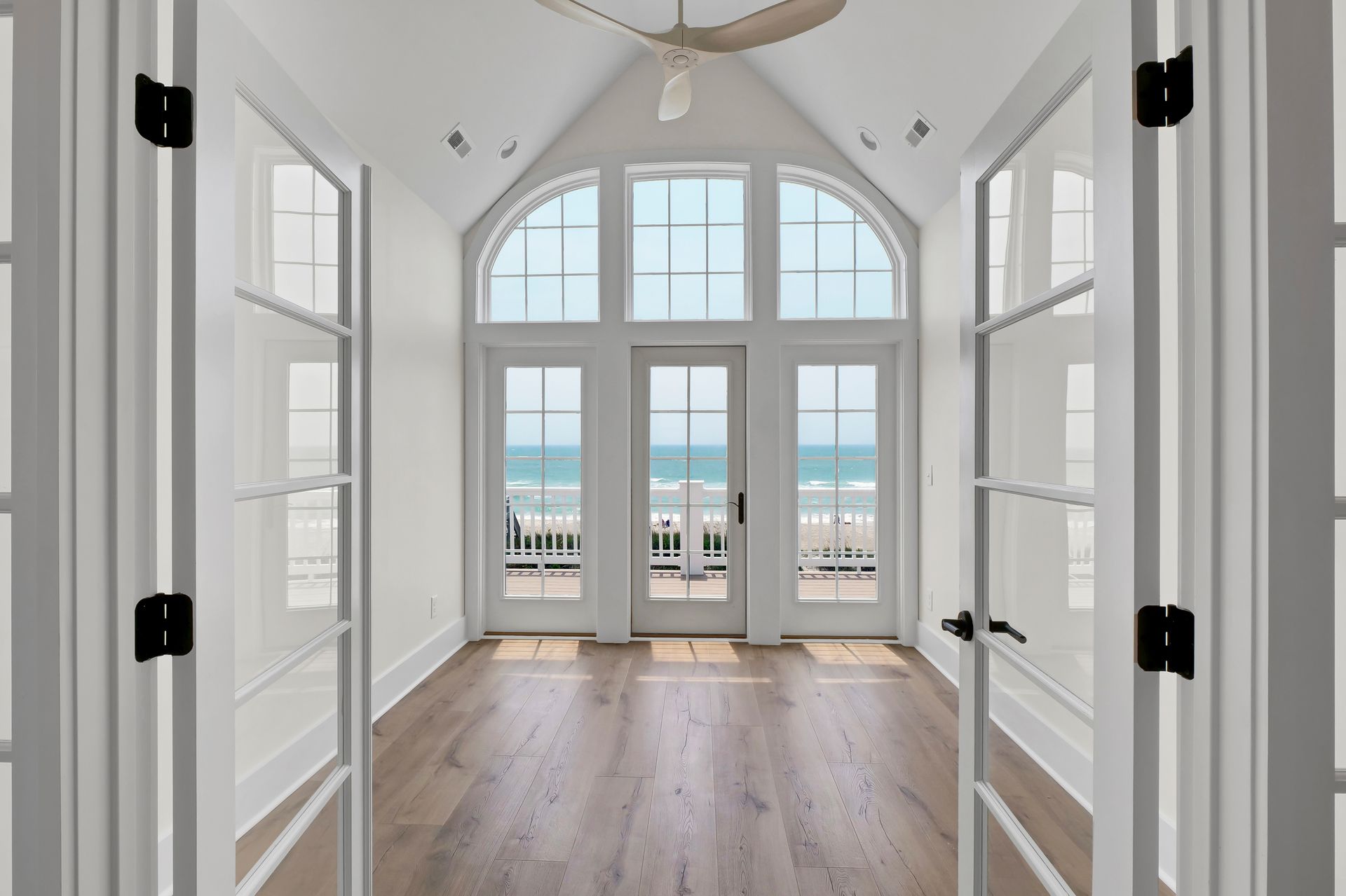 An empty room with a ceiling fan and a view of the ocean.