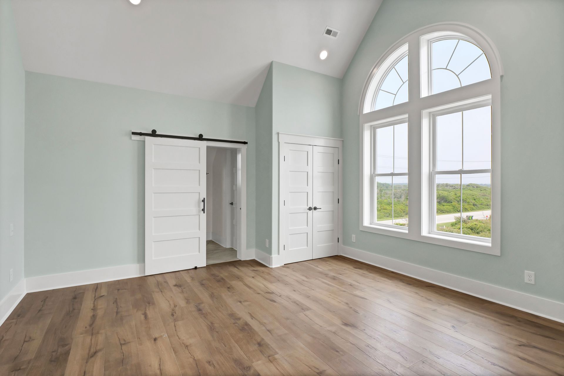 An empty room with hardwood floors and a sliding barn door.