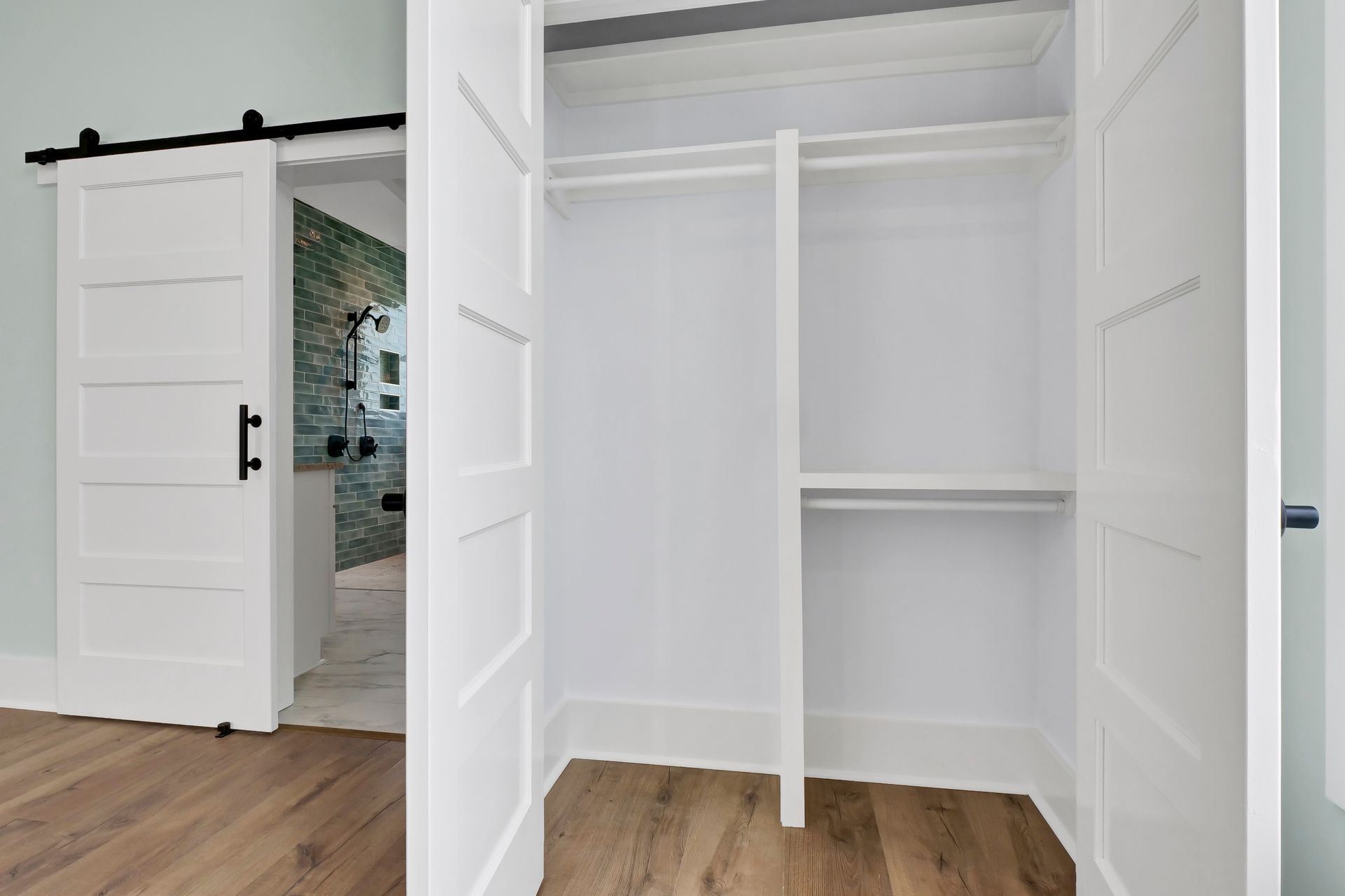 A closet with sliding barn doors and wooden floors.