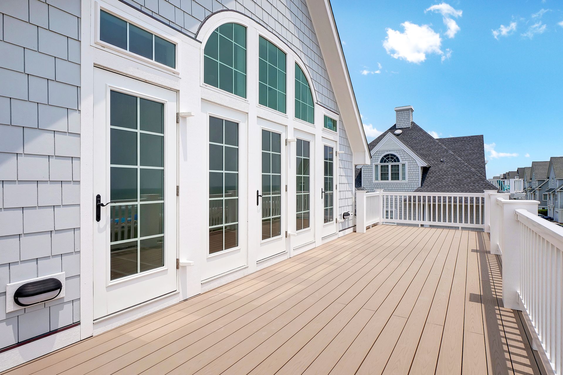 A large deck with a white railing and lots of windows