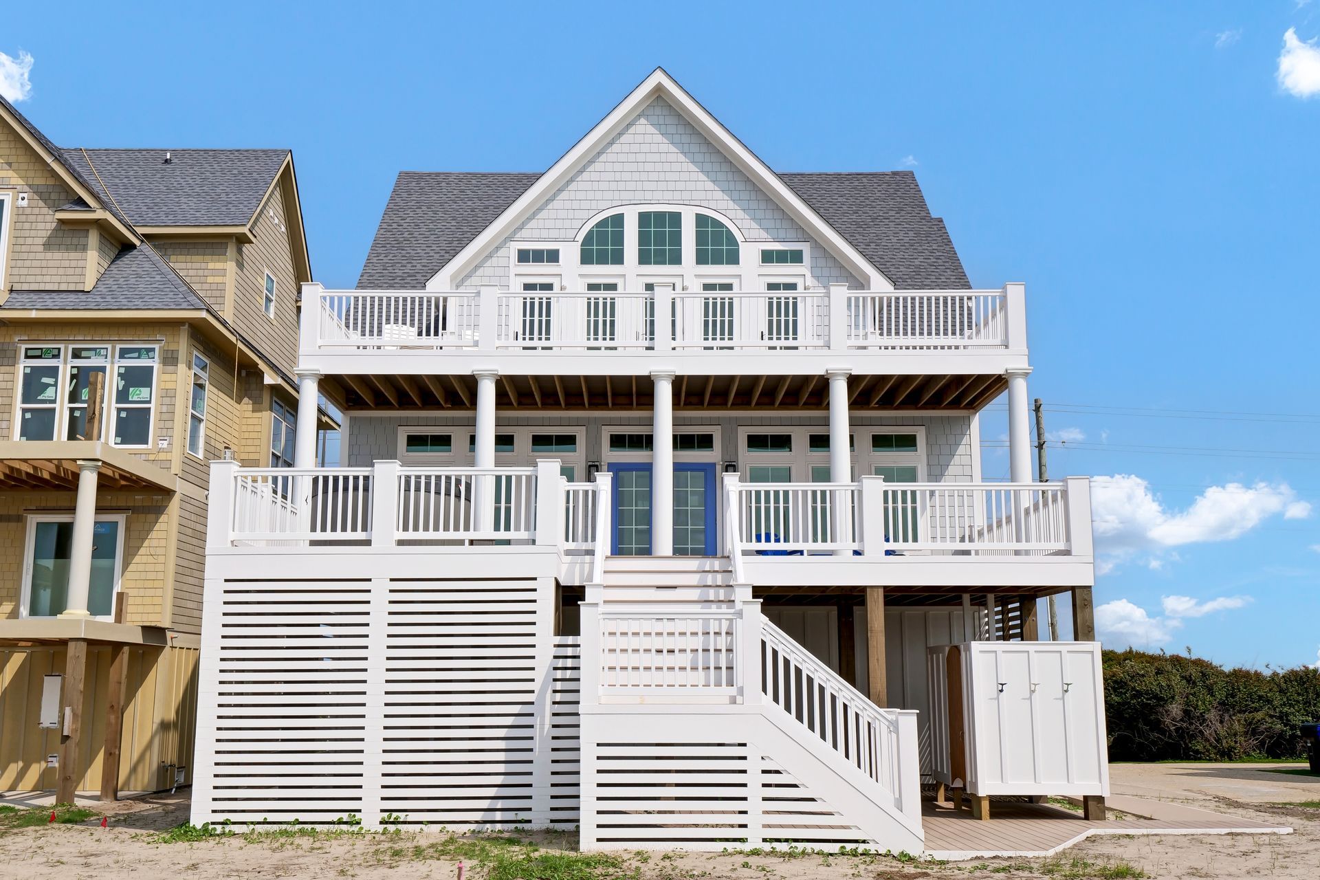 A large white house is sitting on top of a sandy beach.