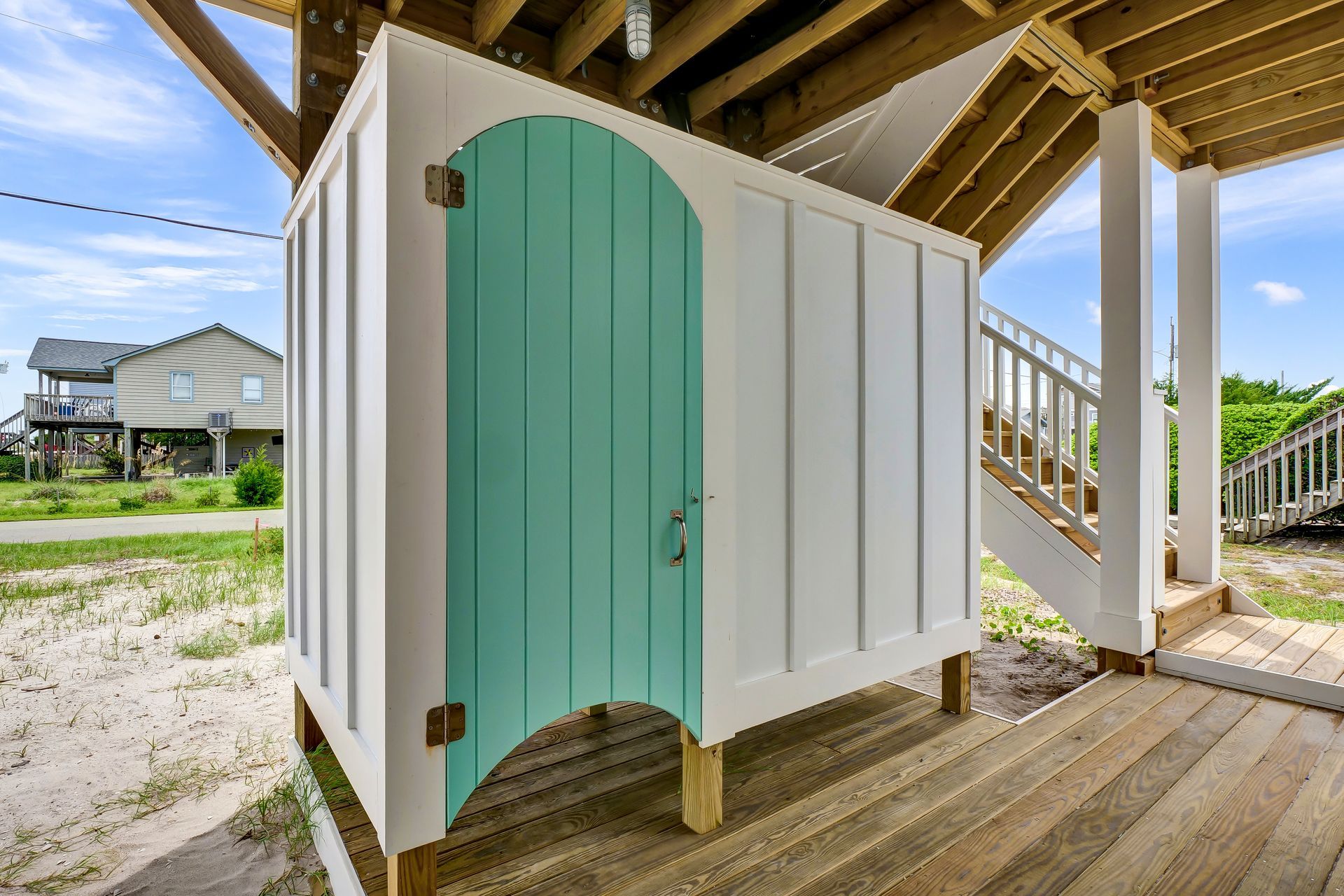 A white shed with a blue door is on a wooden deck.