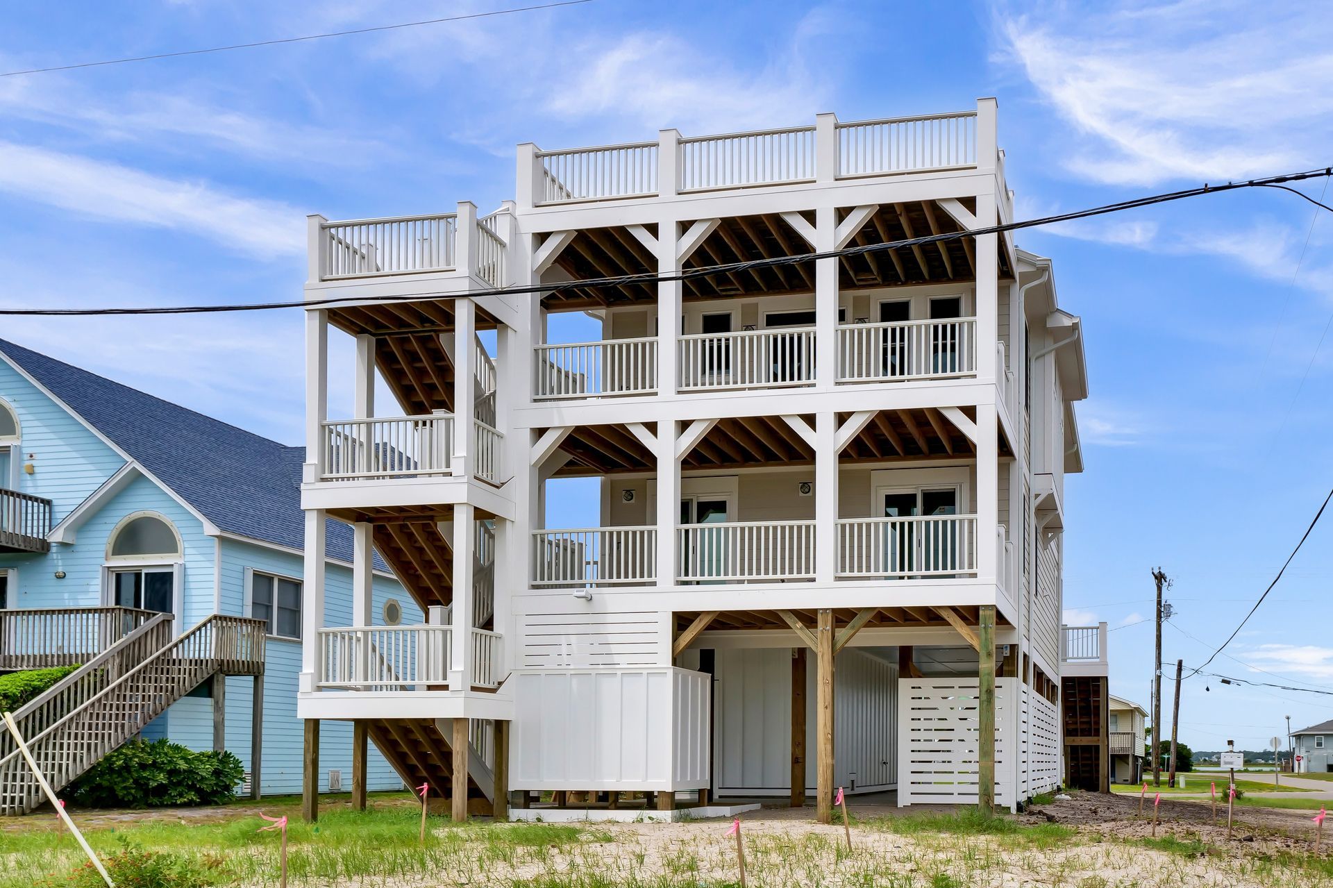 A large white house on stilts with a blue house in the background.
