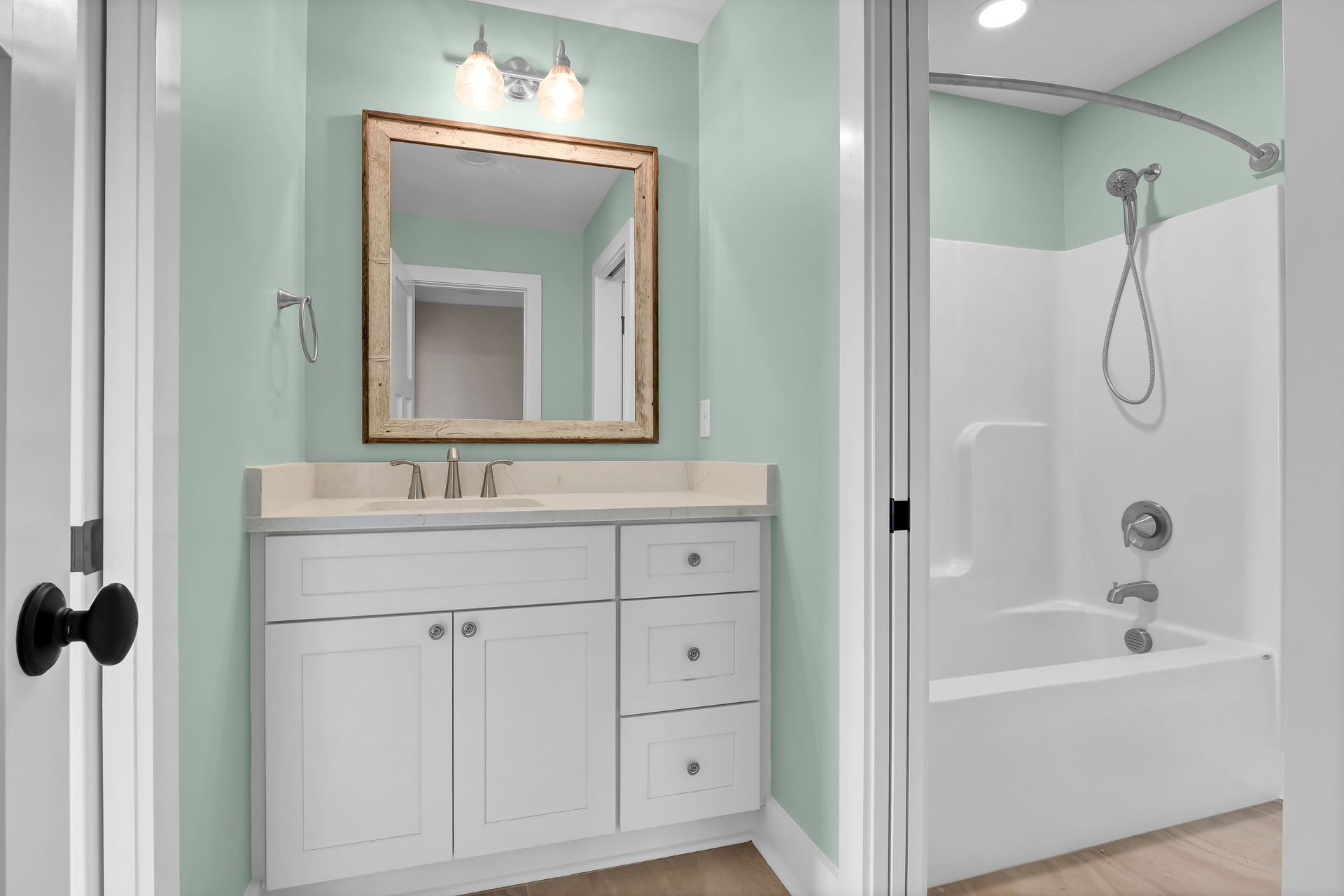 A bathroom with a sink , mirror , tub and shower.