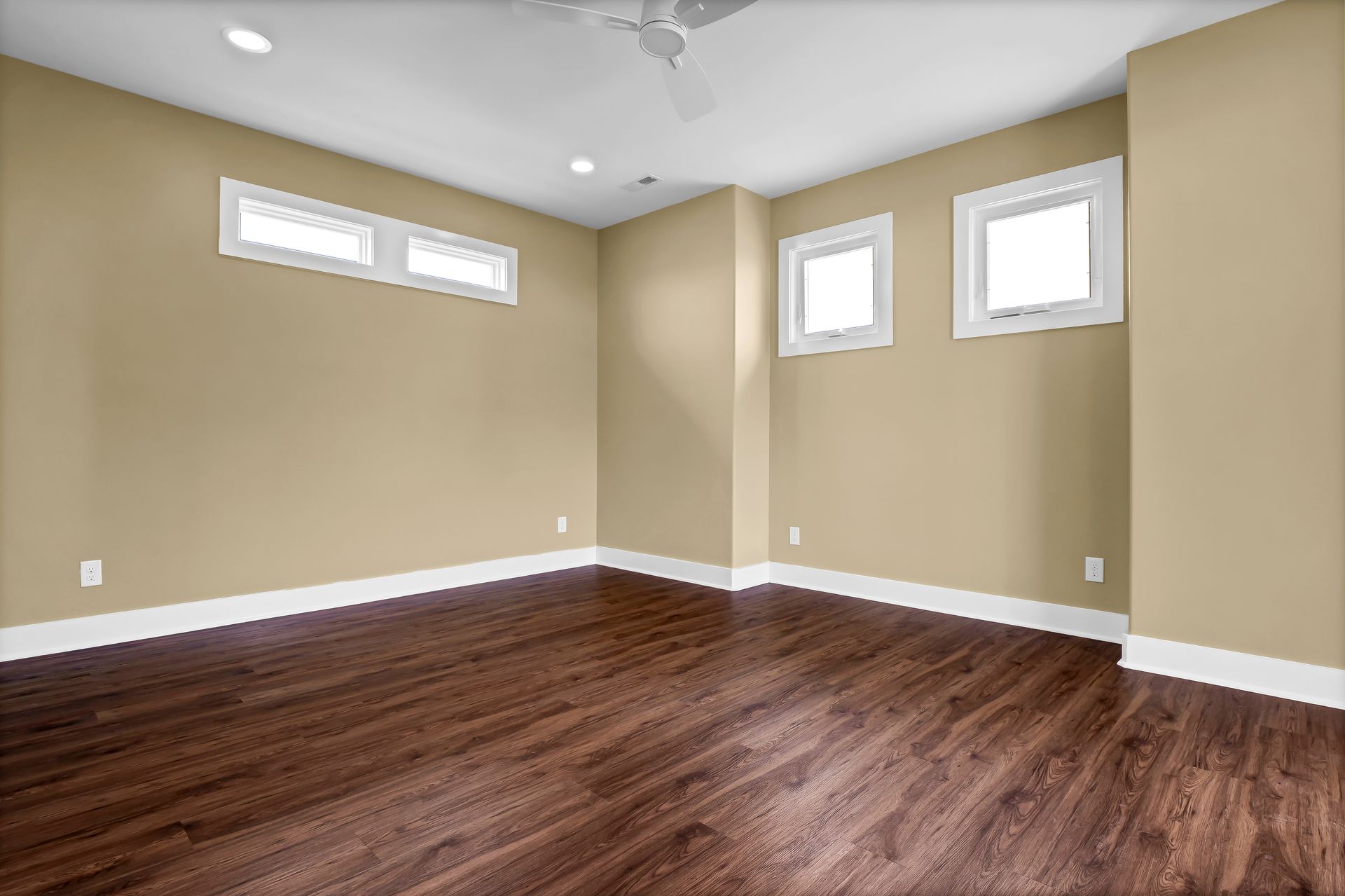 An empty room with hardwood floors and tan walls.