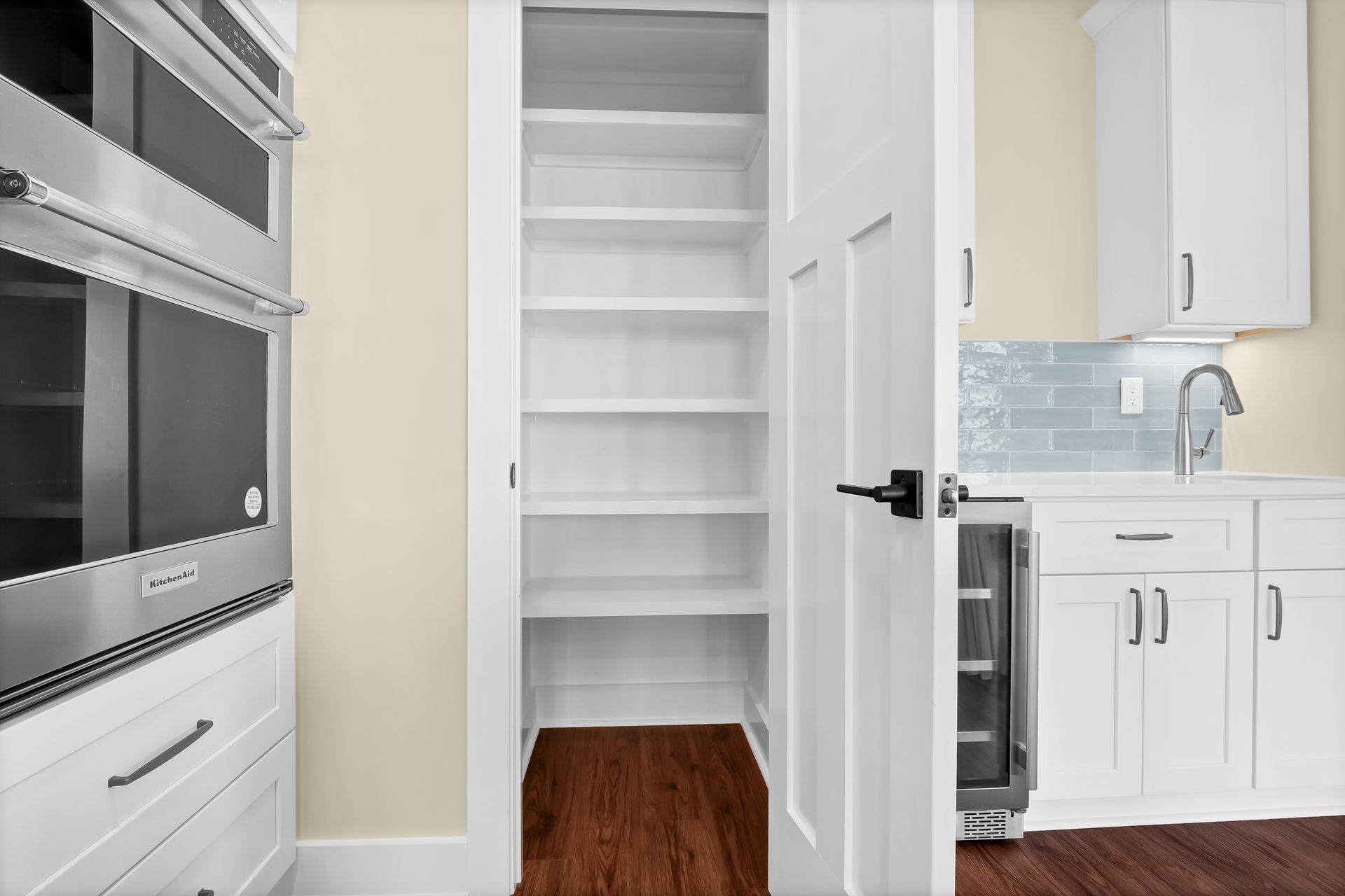 A kitchen with white cabinets , stainless steel appliances and a pantry.