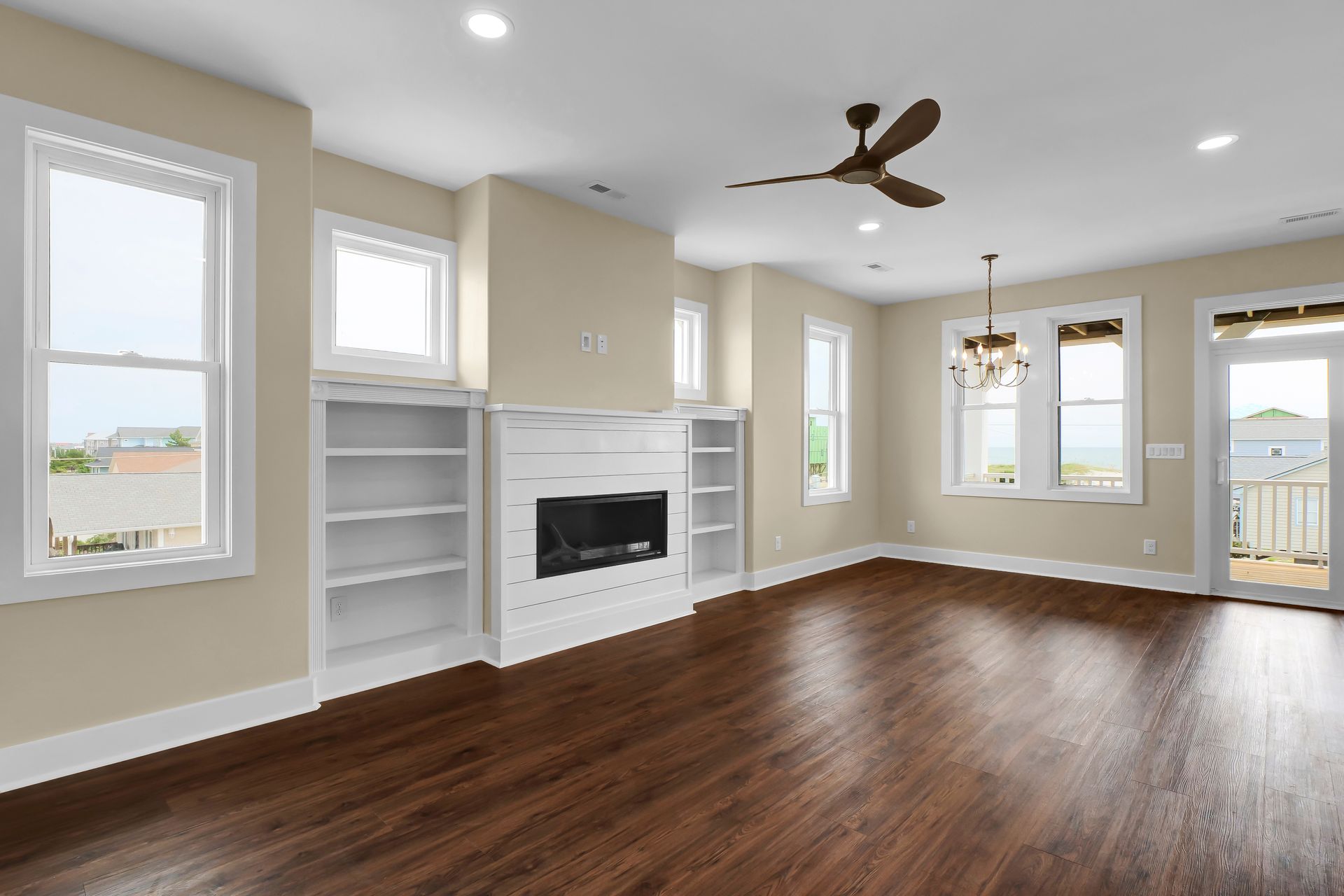 An empty living room with hardwood floors , a fireplace and a ceiling fan.