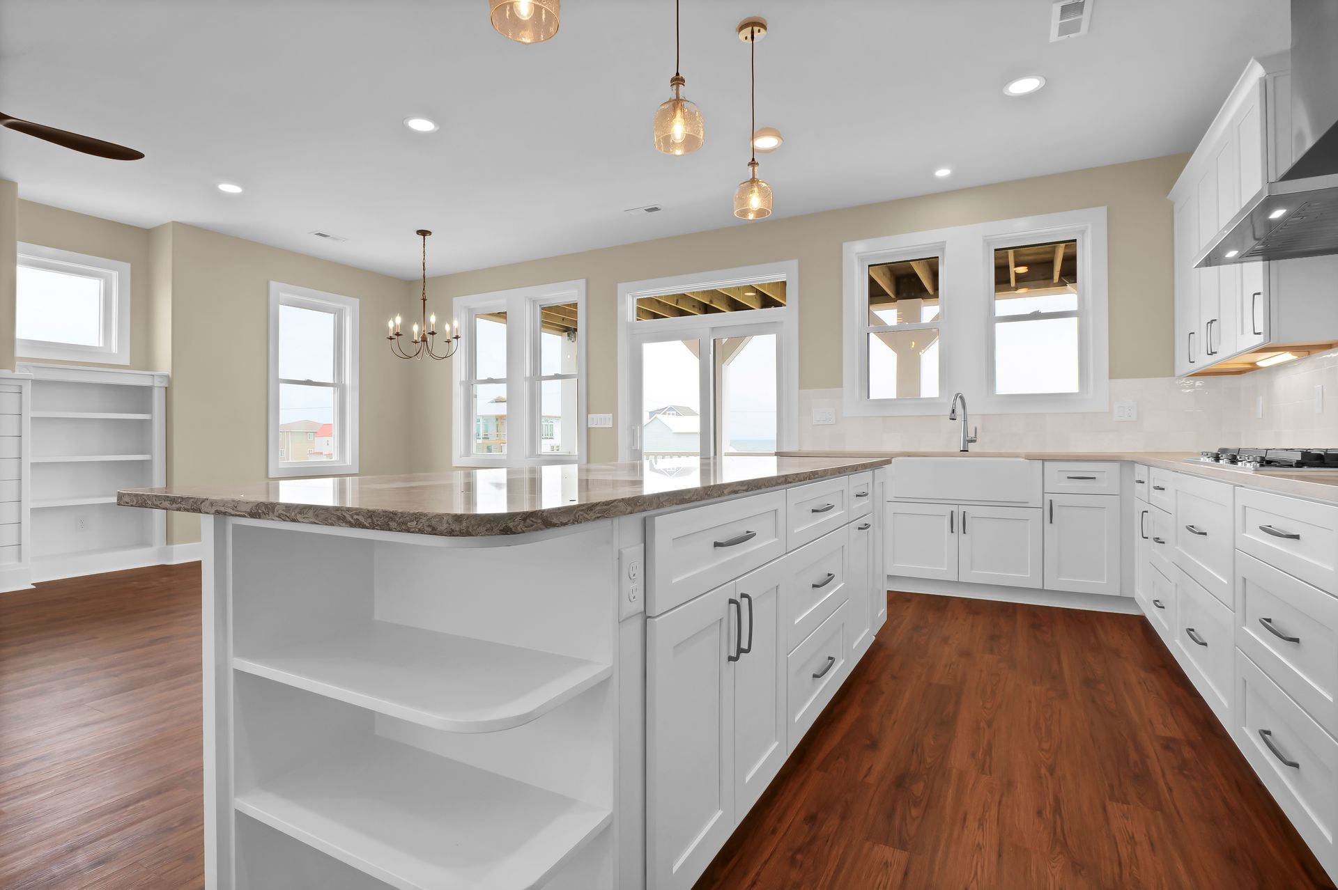 A kitchen with white cabinets , granite counter tops , and hardwood floors.