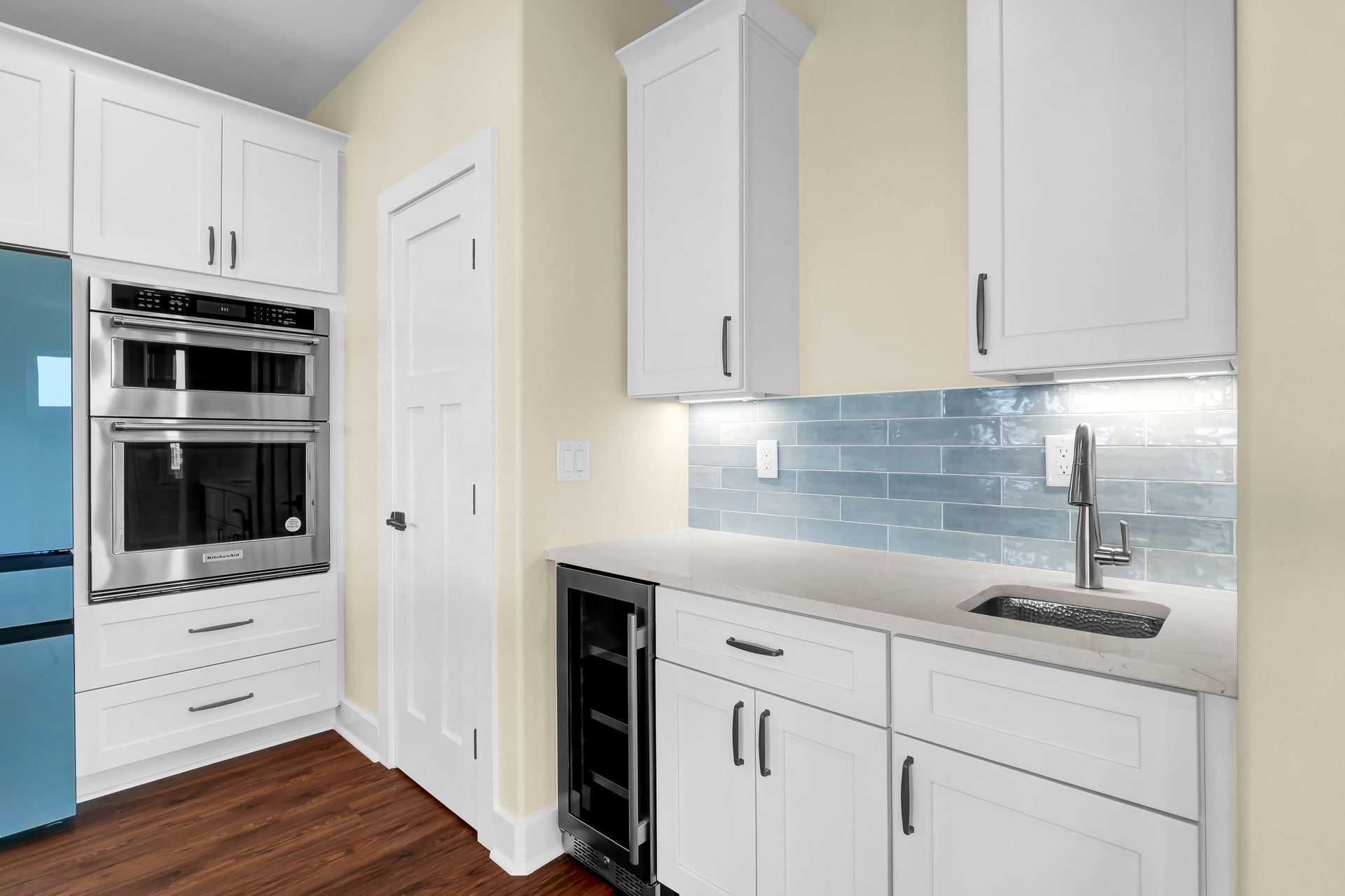 A kitchen with white cabinets , stainless steel appliances , a sink , and a refrigerator.
