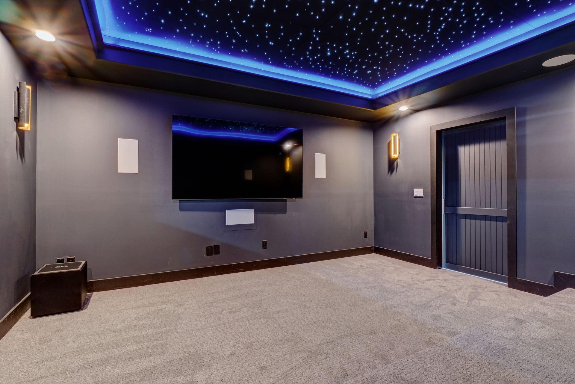 A home theater with a flat screen tv and a starry ceiling.