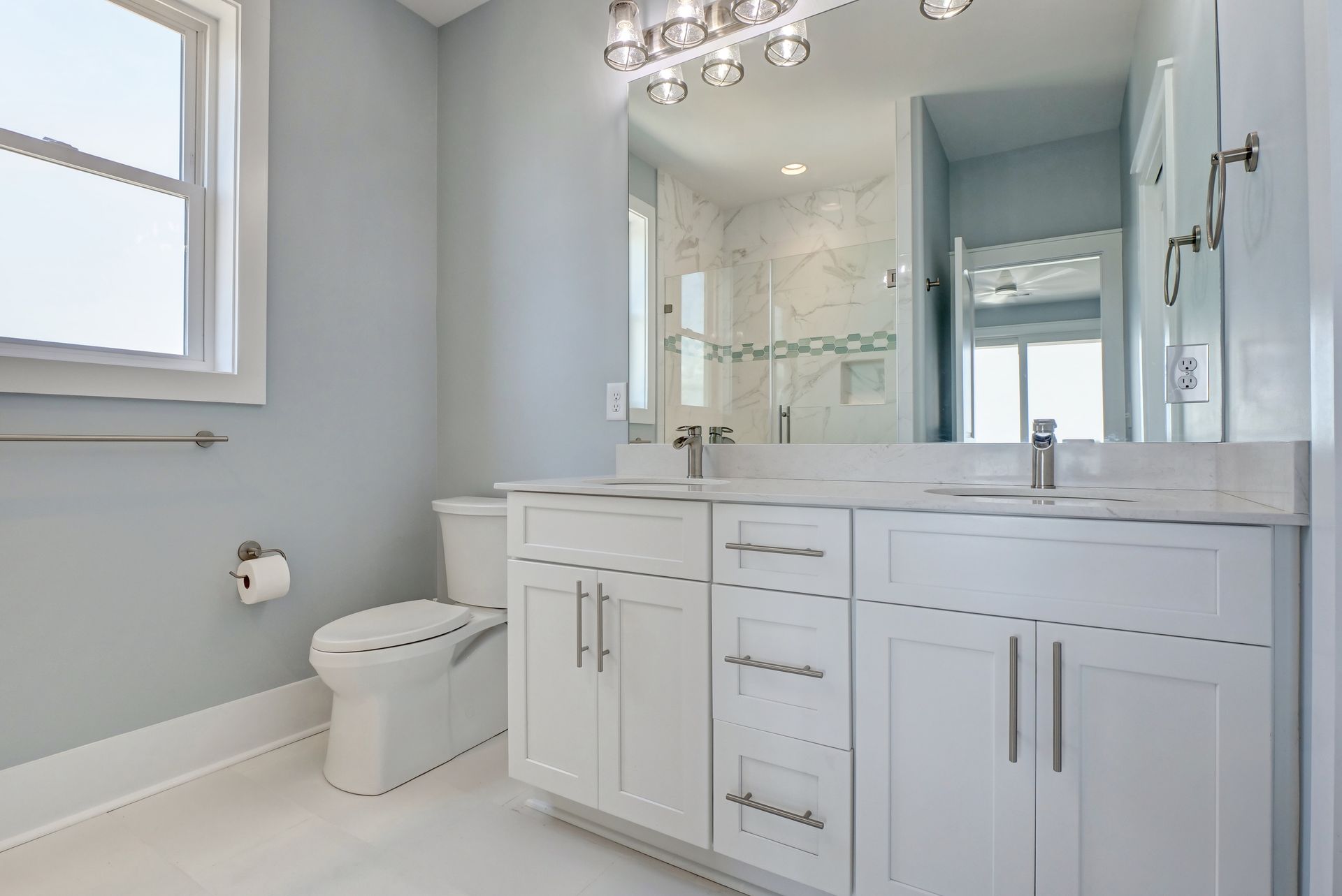 A bathroom with two sinks , a toilet , and a large mirror.
