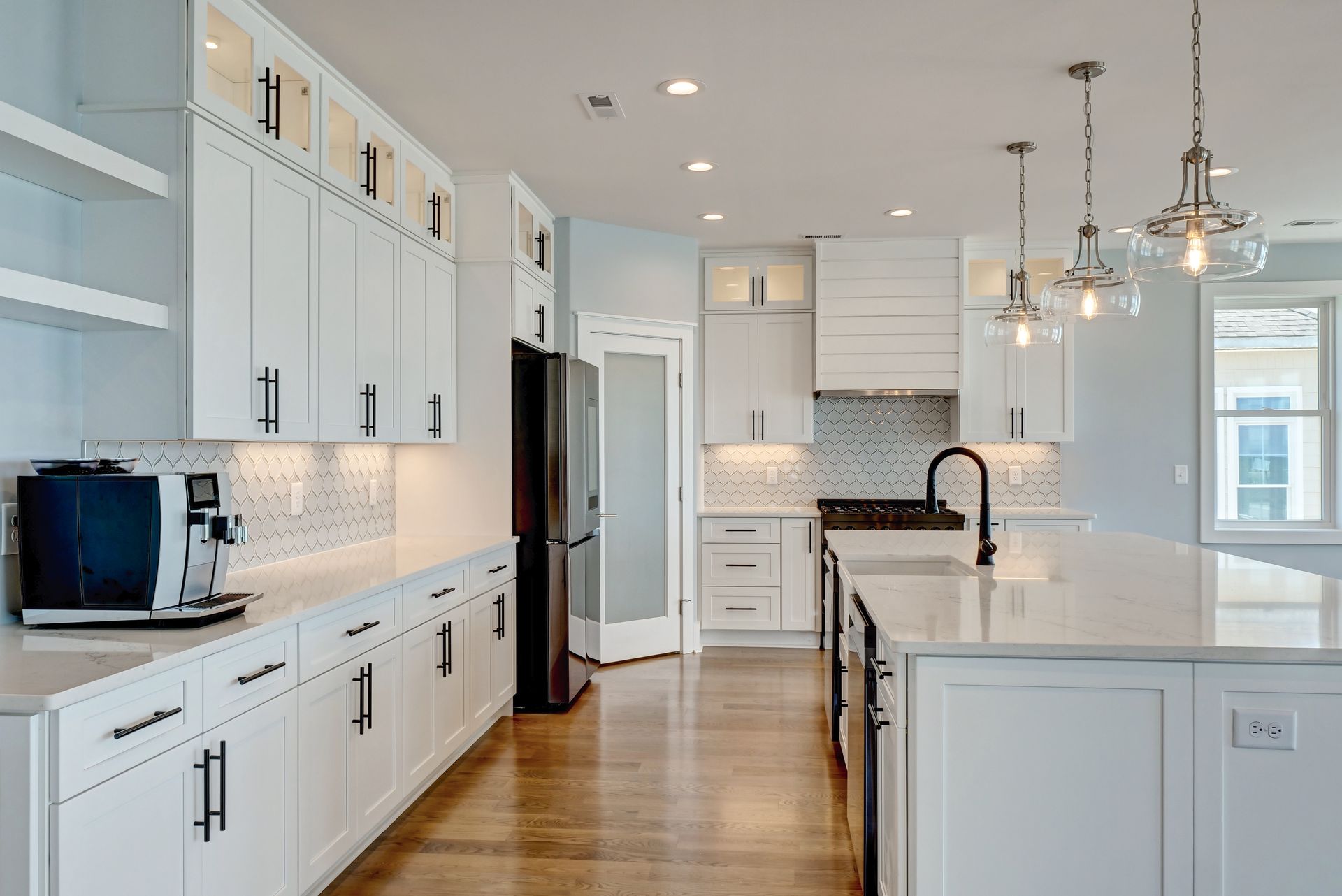 A kitchen with white cabinets , granite counter tops , stainless steel appliances and a large island.