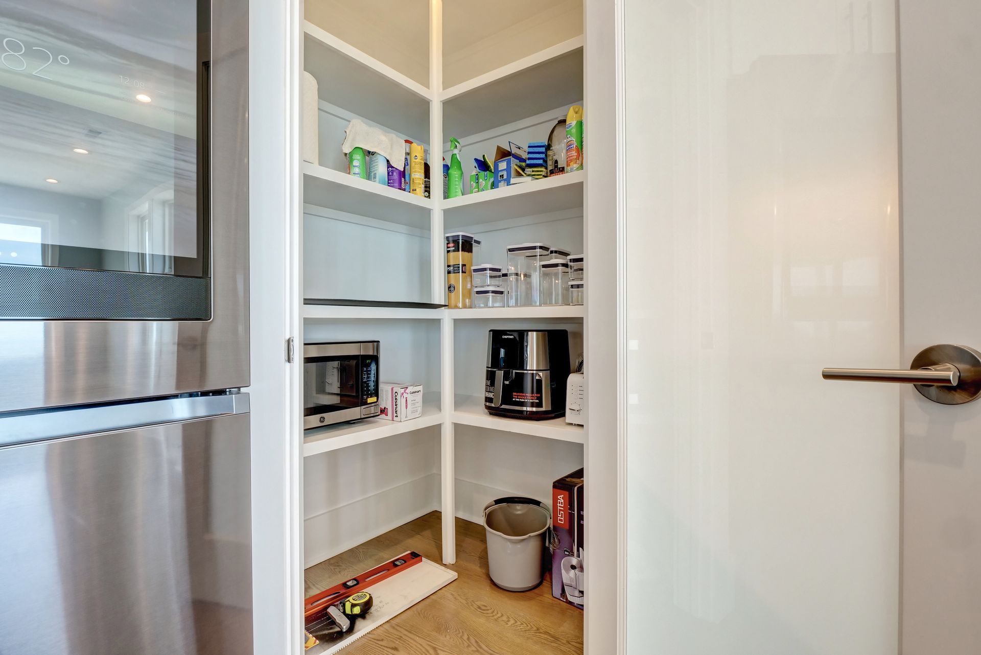 A pantry in a kitchen with stainless steel appliances and shelves.