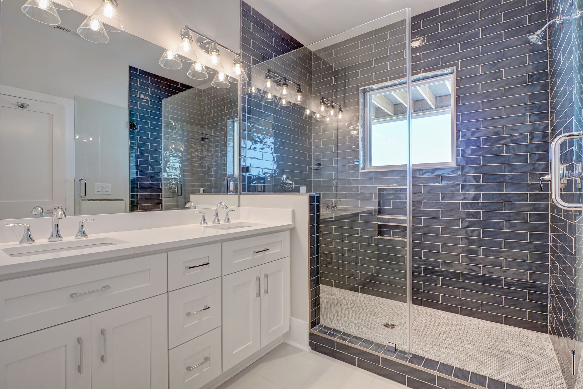 A bathroom with two sinks , a walk in shower and a large mirror.