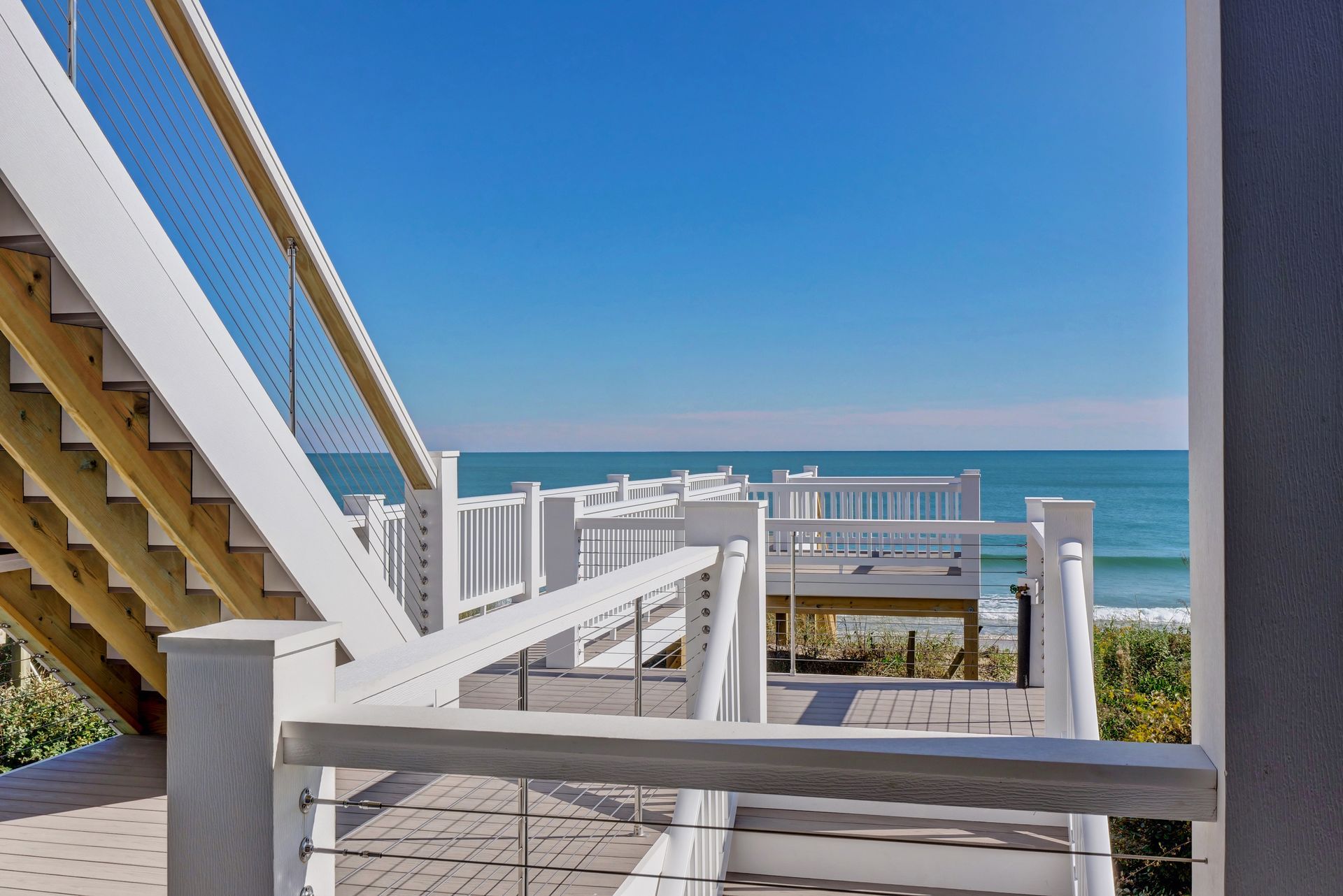 A view of the ocean from a balcony with stairs leading up to it.