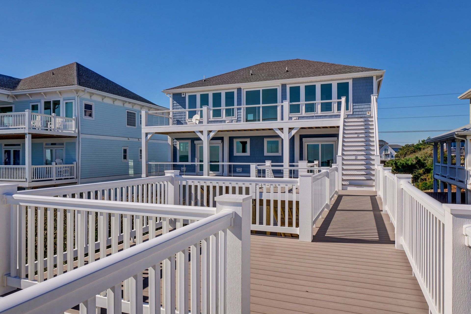 A blue house with a white deck and stairs leading to it.