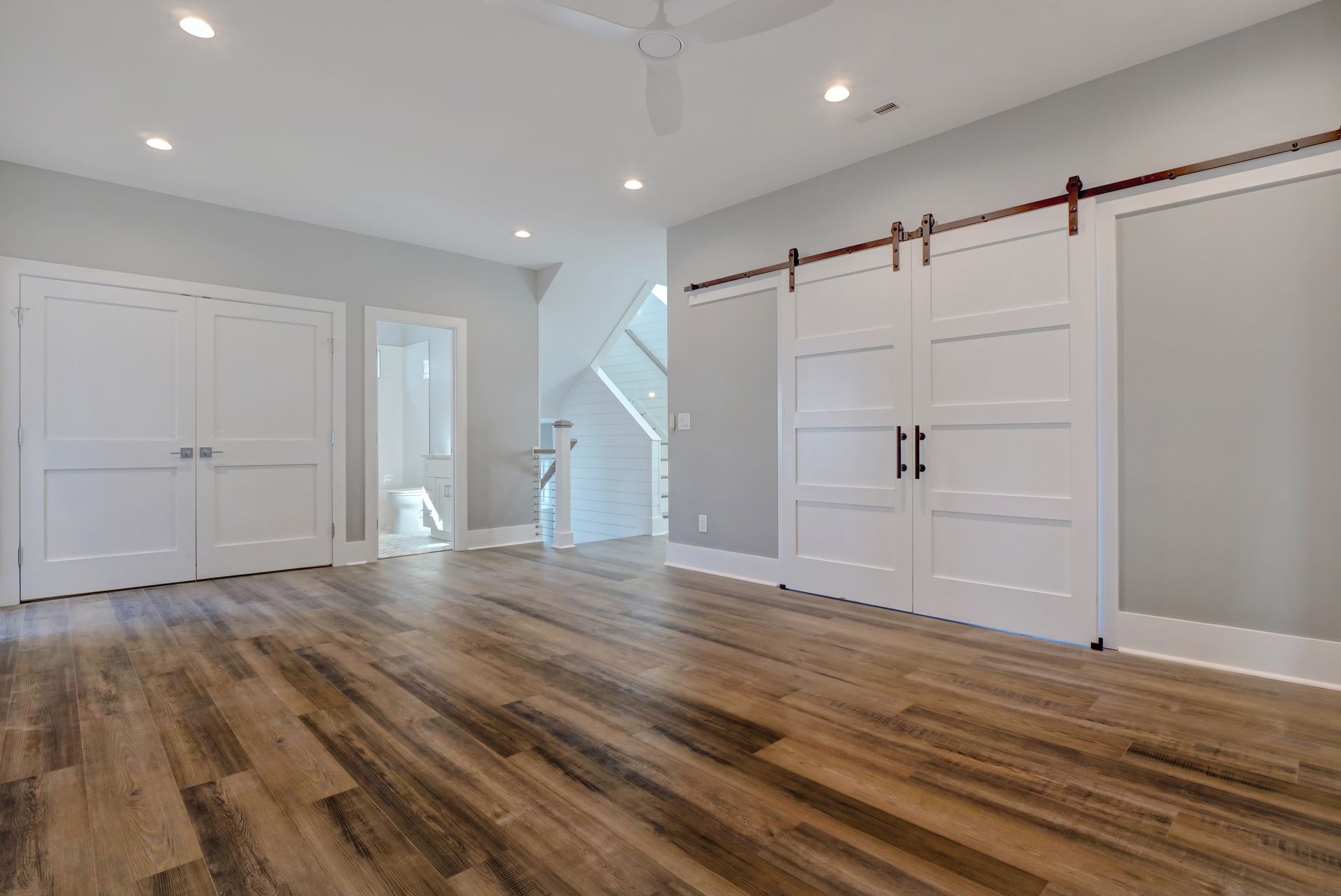 A large empty room with hardwood floors and sliding barn doors.