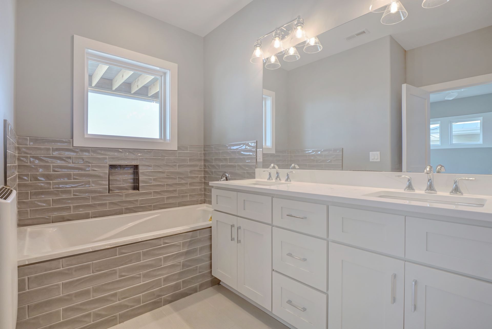 A bathroom with two sinks , a tub , and a large mirror.