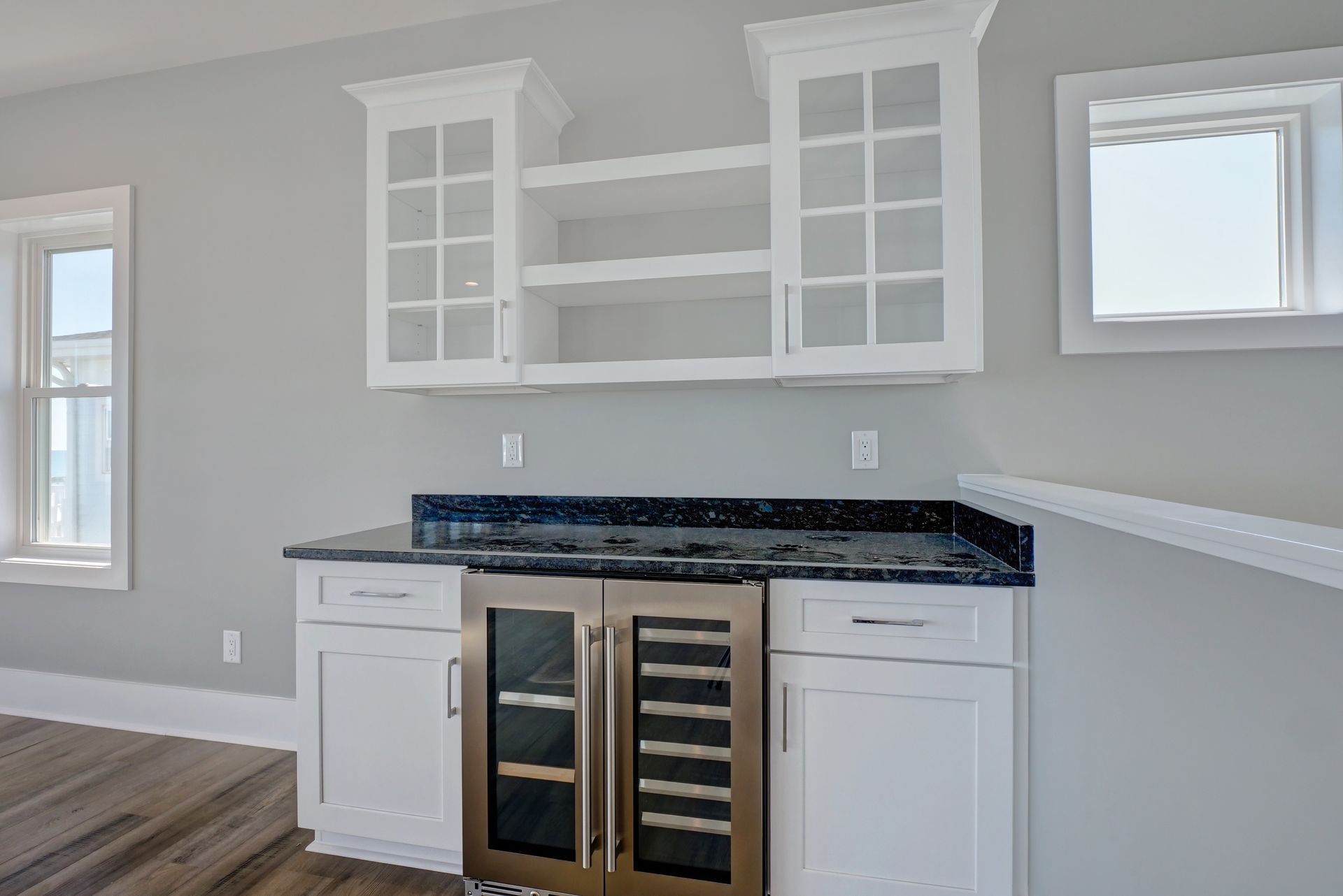 A kitchen with white cabinets and a wine cooler.