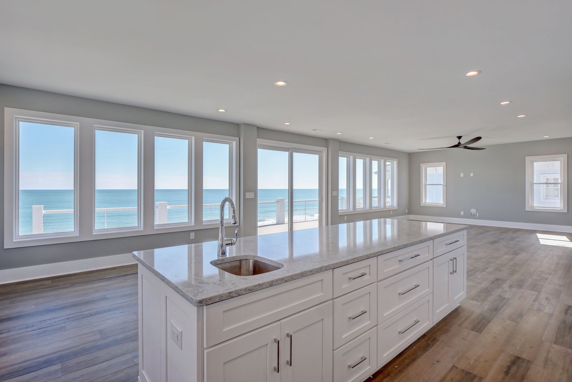 A kitchen with a large island and a sink and a view of the ocean.