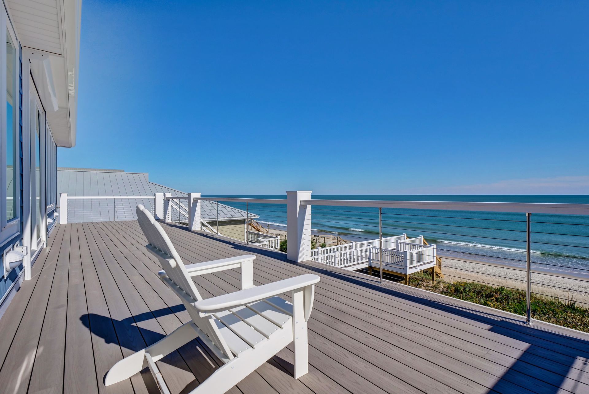 There are two chairs on the deck with a view of the ocean.
