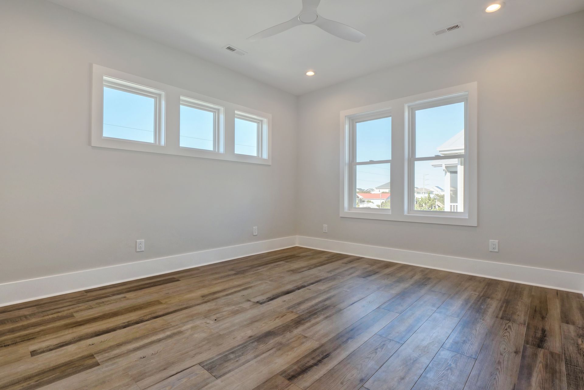 An empty bedroom with hardwood floors and a ceiling fan.