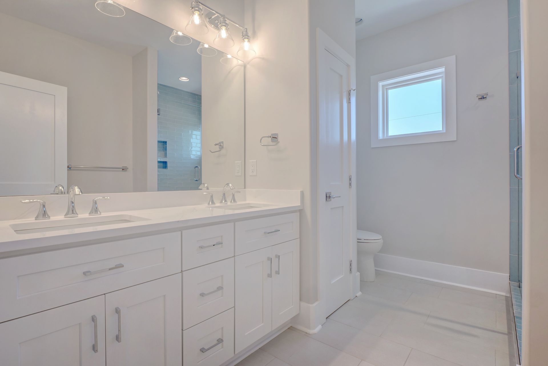A bathroom with two sinks , a toilet , and a window.