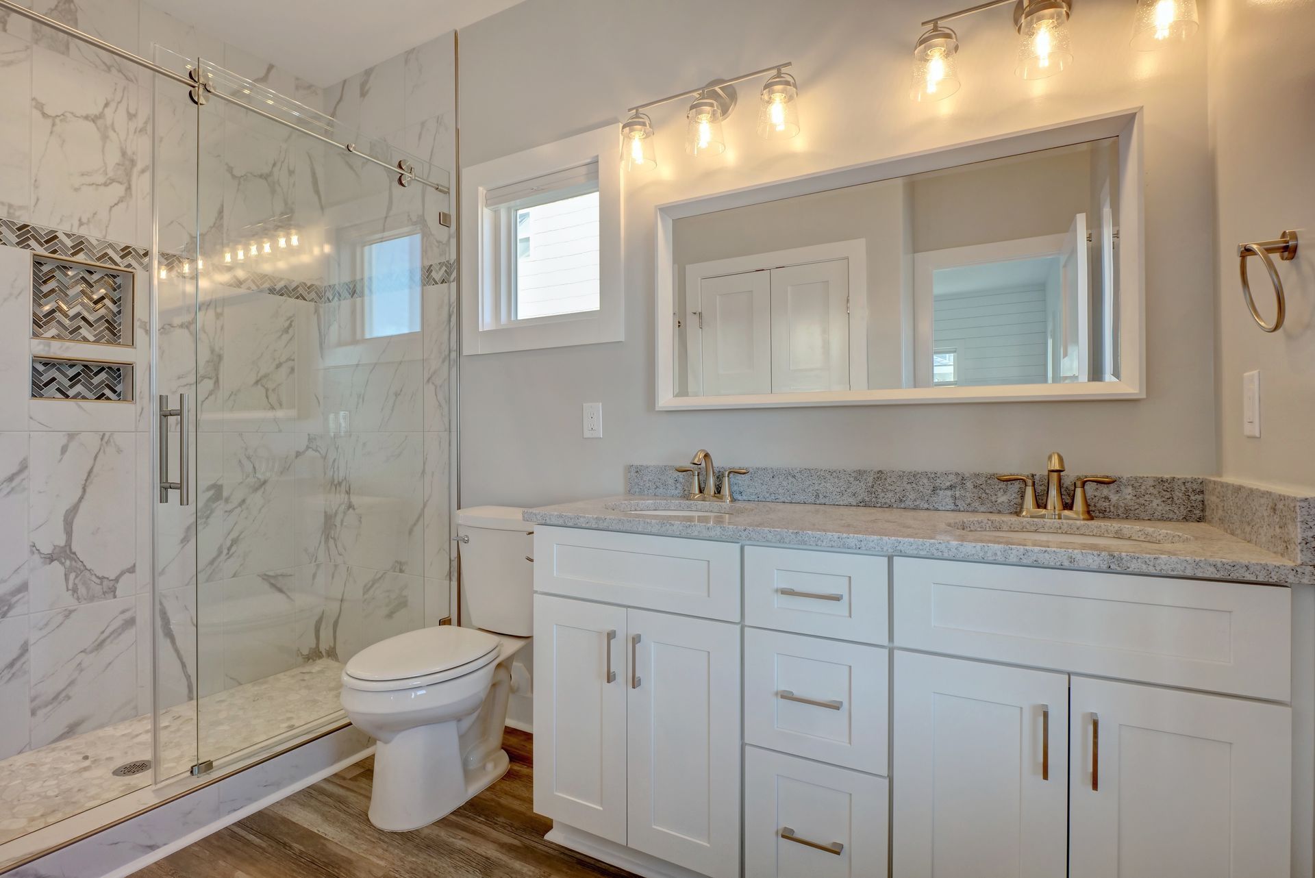 A bathroom with a toilet , sink , mirror and walk in shower.