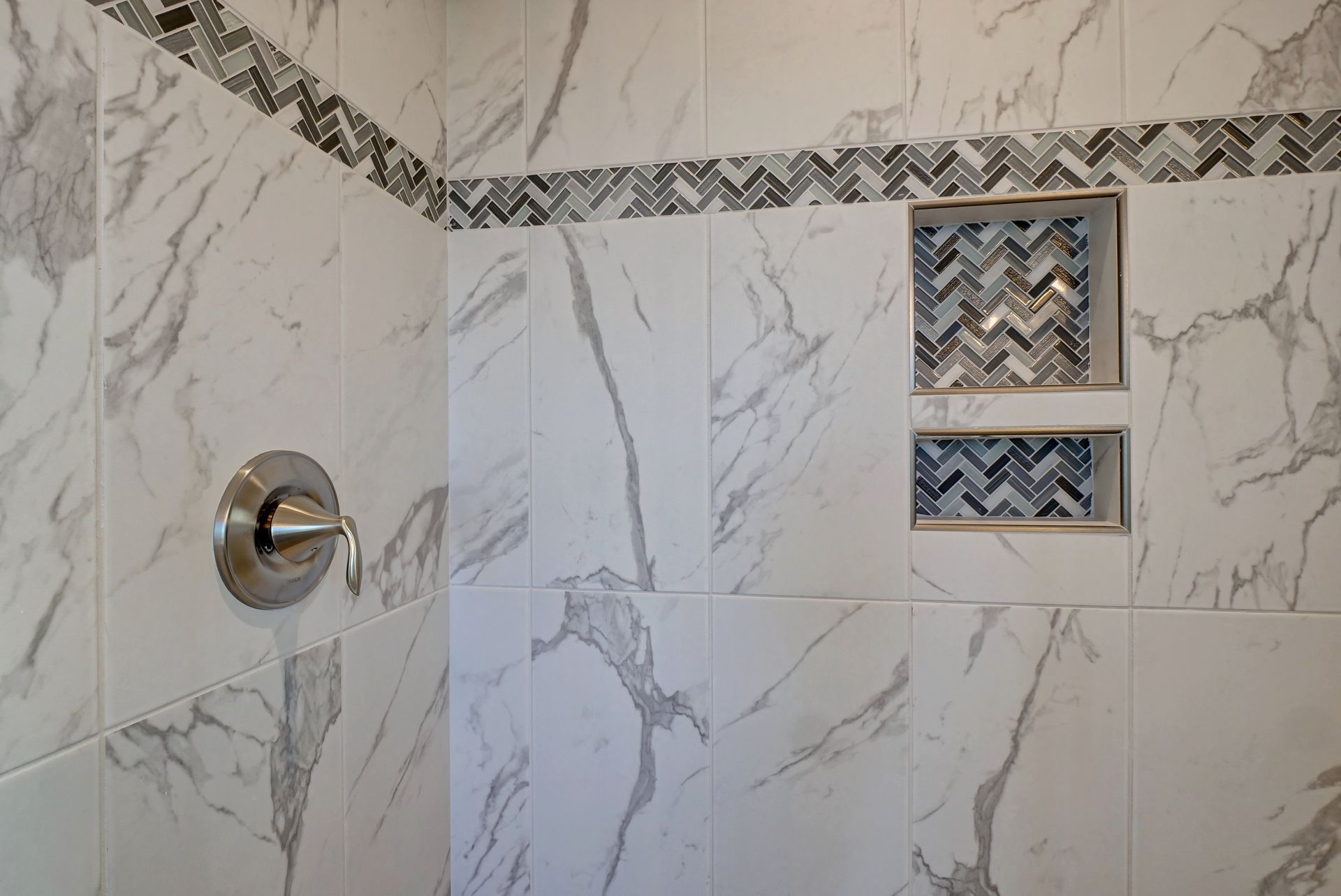 A bathroom with marble tiles and a shower head.