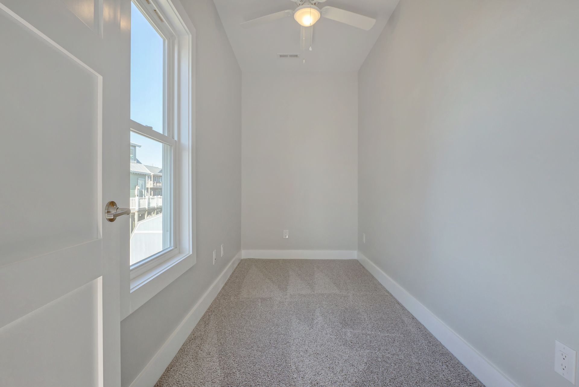 An empty room with a ceiling fan and a window.