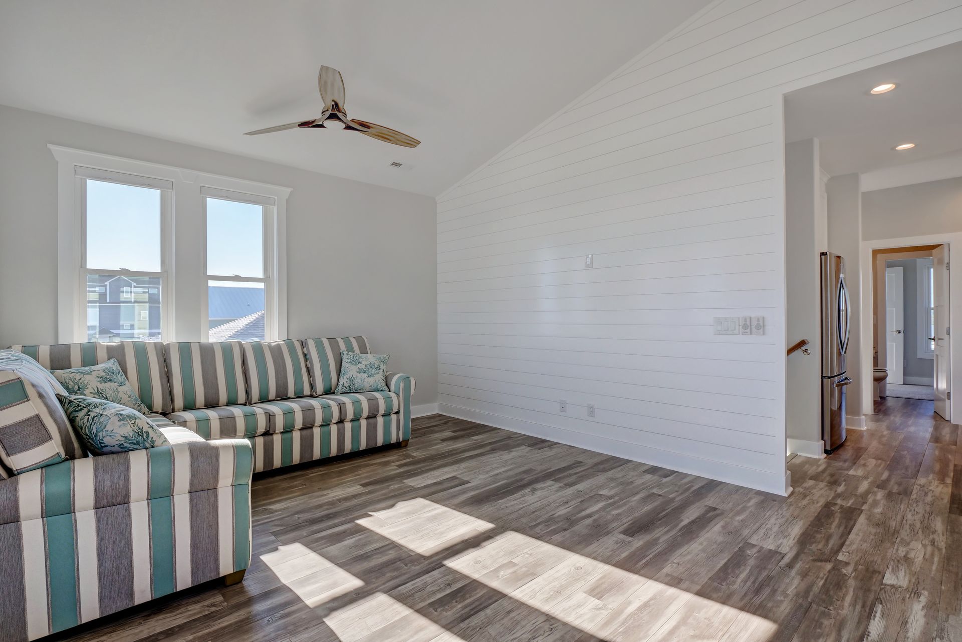 A living room with a striped couch and a ceiling fan.