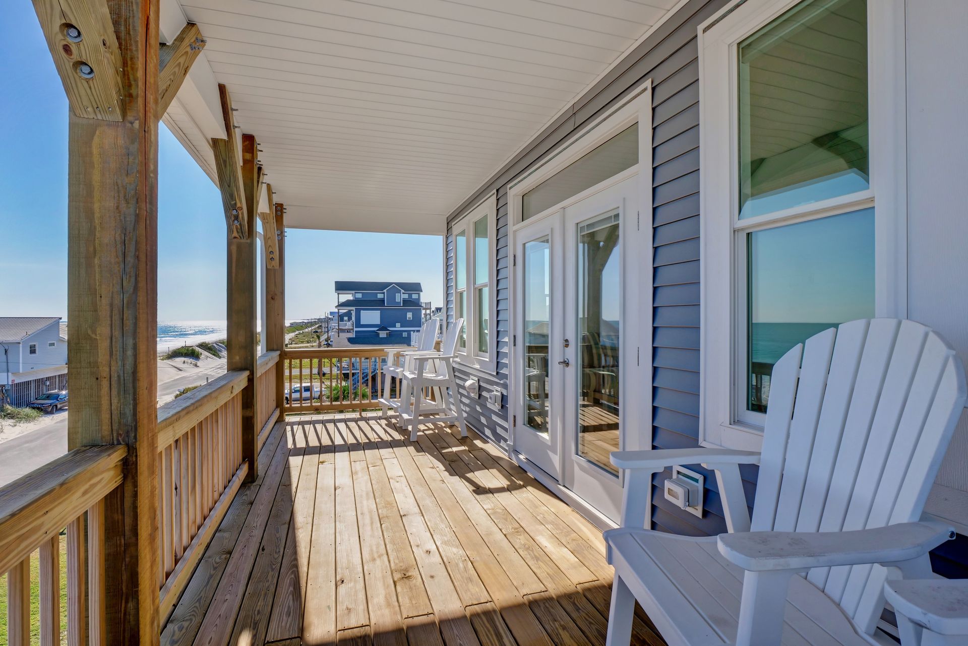 There is a large porch with chairs and a view of the ocean.