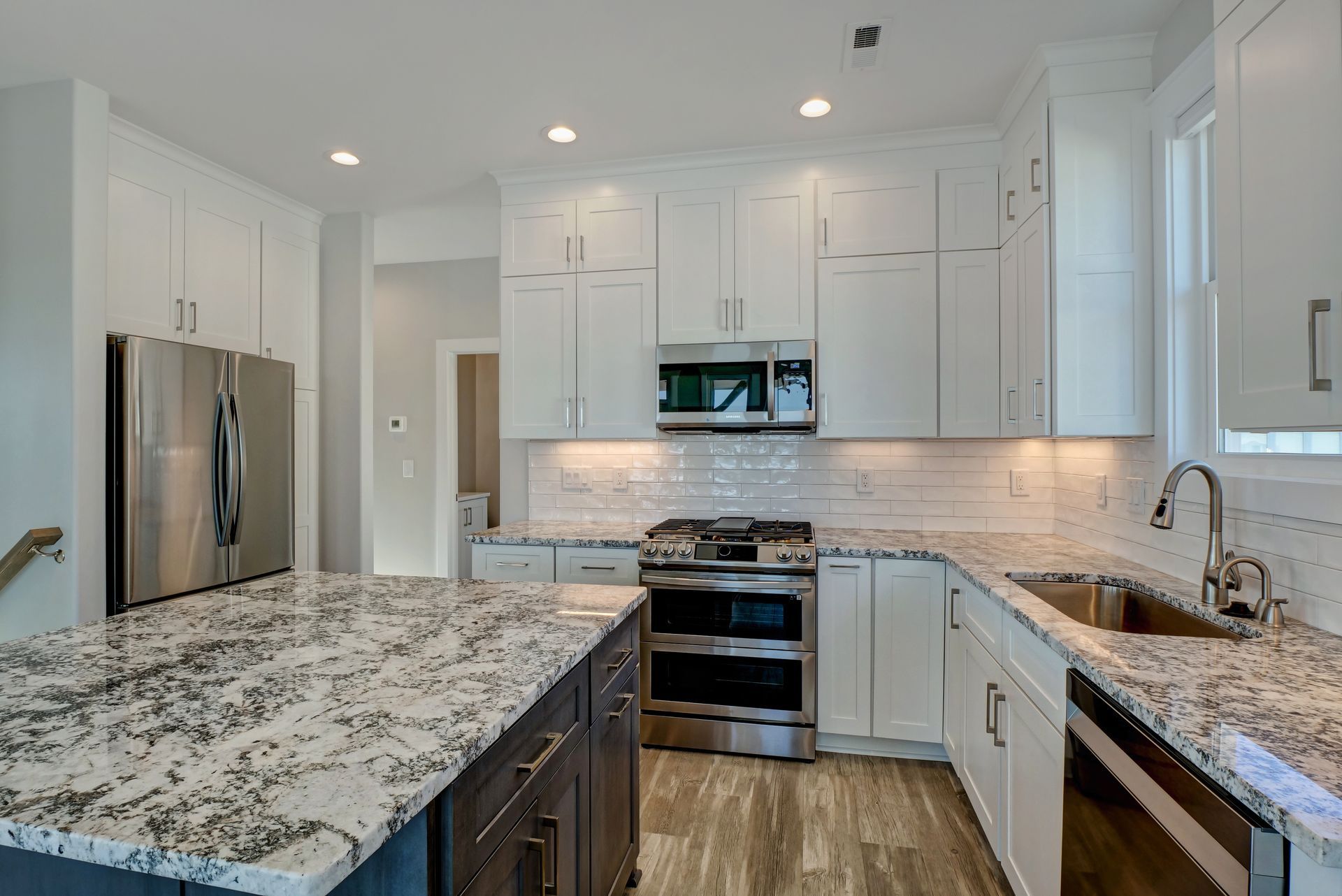 A kitchen with granite counter tops , stainless steel appliances , and white cabinets.