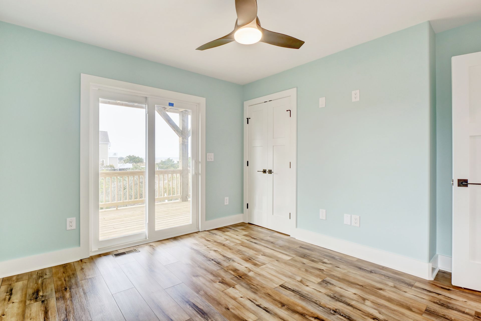 An empty room with hardwood floors and a ceiling fan.