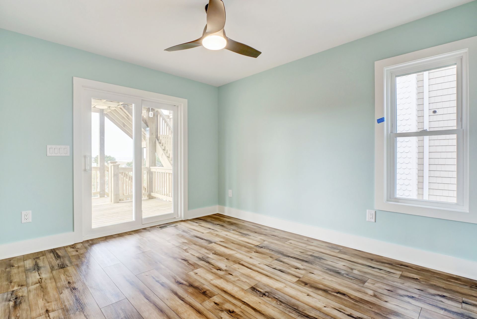 An empty room with hardwood floors and a ceiling fan.