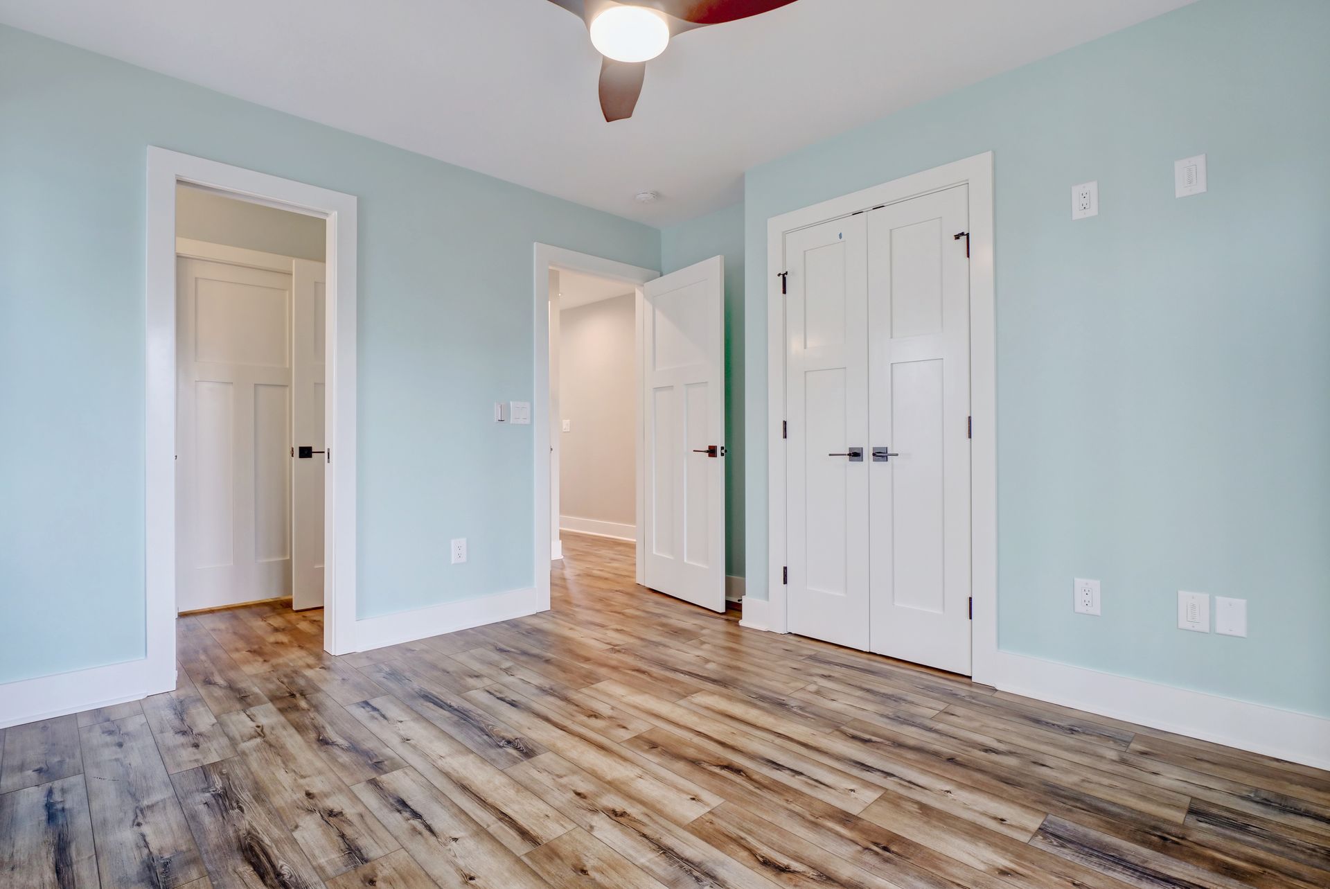 An empty bedroom with hardwood floors and a ceiling fan.